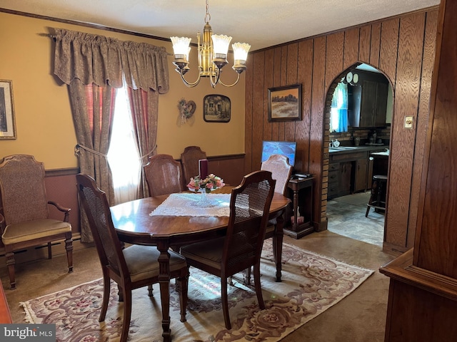 dining room with a chandelier, a textured ceiling, and wood walls