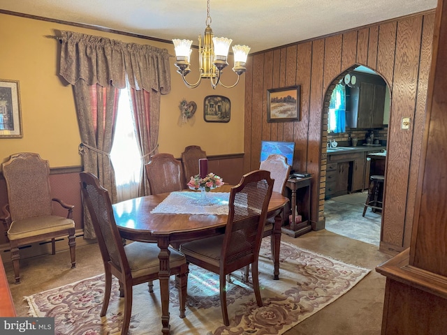 dining area with a notable chandelier, a textured ceiling, and wooden walls