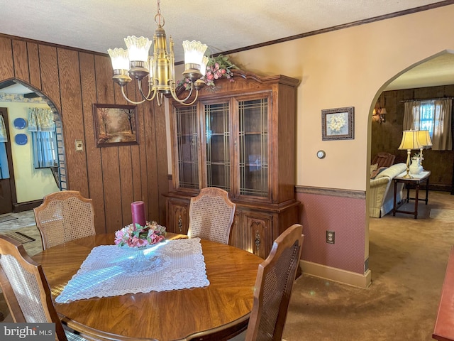 dining area with a chandelier, carpet, a textured ceiling, and ornamental molding