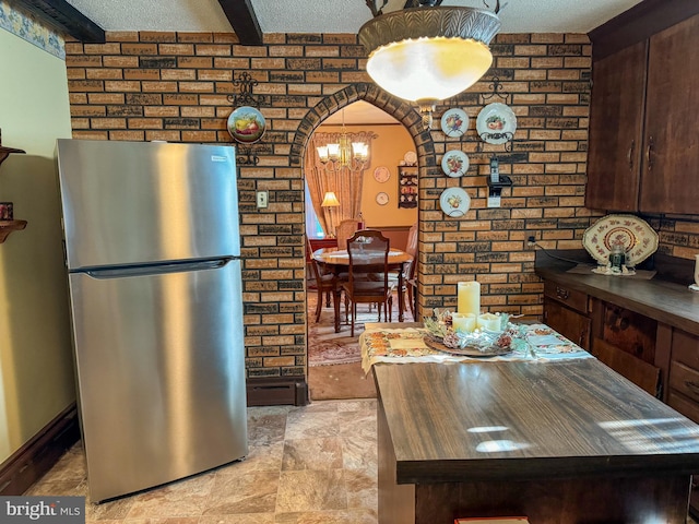 kitchen featuring a chandelier, dark brown cabinets, a textured ceiling, and stainless steel refrigerator