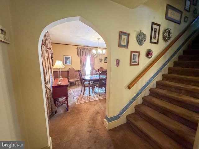 stairs with carpet and an inviting chandelier