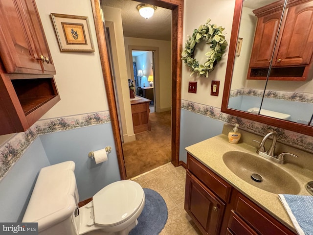 bathroom with vanity, toilet, and a textured ceiling