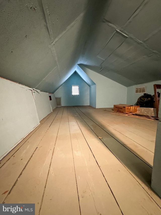 additional living space with light hardwood / wood-style floors and vaulted ceiling