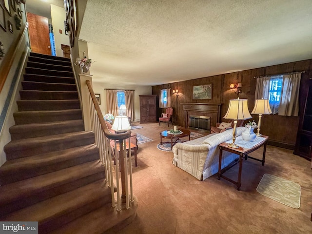 living room featuring wood walls, plenty of natural light, carpet, and a textured ceiling