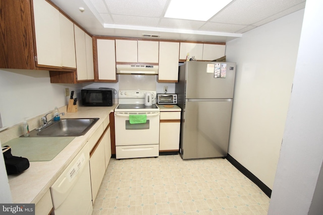 kitchen with white cabinets, a drop ceiling, white appliances, and sink