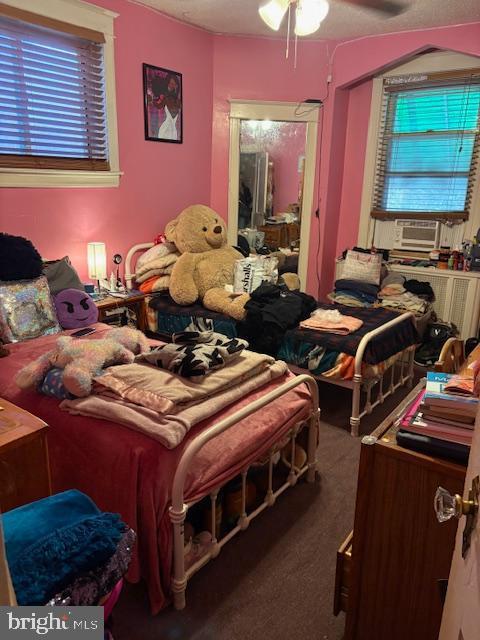 bedroom with dark colored carpet, ceiling fan, and cooling unit