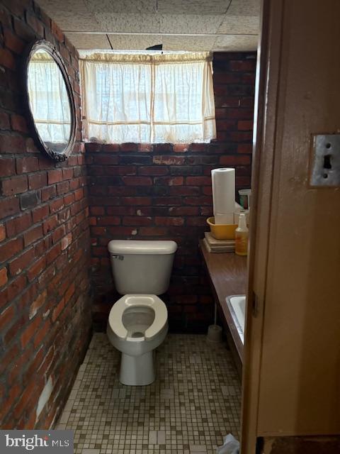 bathroom with toilet and brick wall