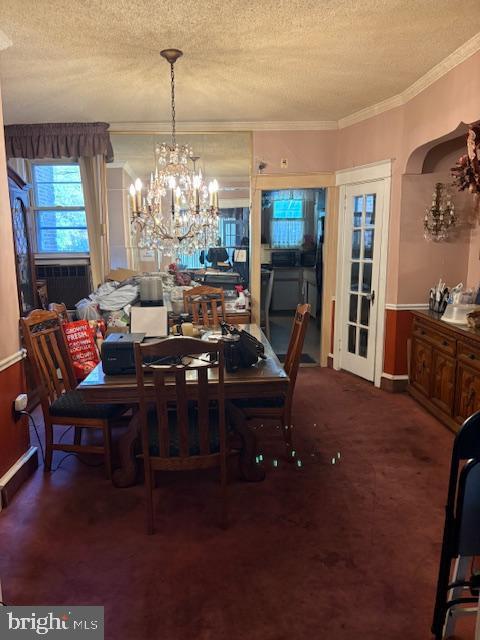 carpeted dining space with a chandelier, a textured ceiling, and ornamental molding