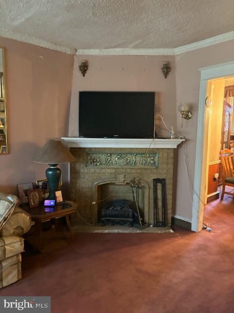 living room with carpet, crown molding, a stone fireplace, and a textured ceiling