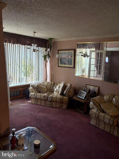 living room featuring carpet flooring, a textured ceiling, and a notable chandelier