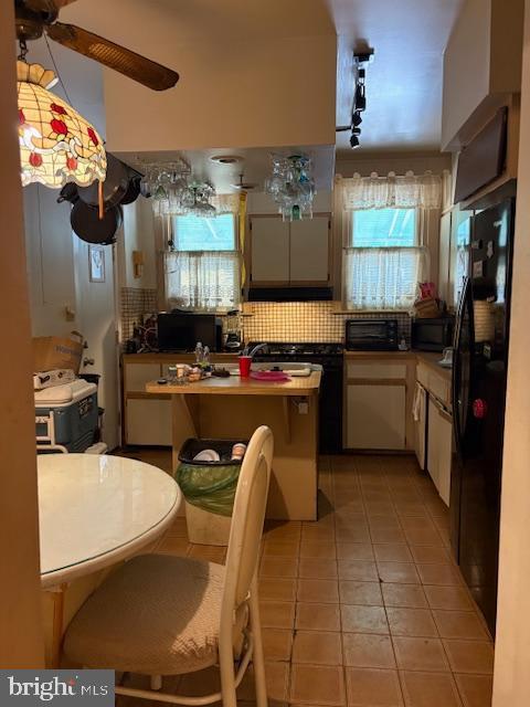 kitchen featuring black appliances, light tile patterned flooring, and backsplash