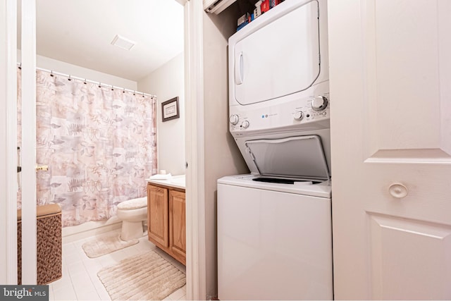 laundry room with light tile patterned flooring and stacked washing maching and dryer