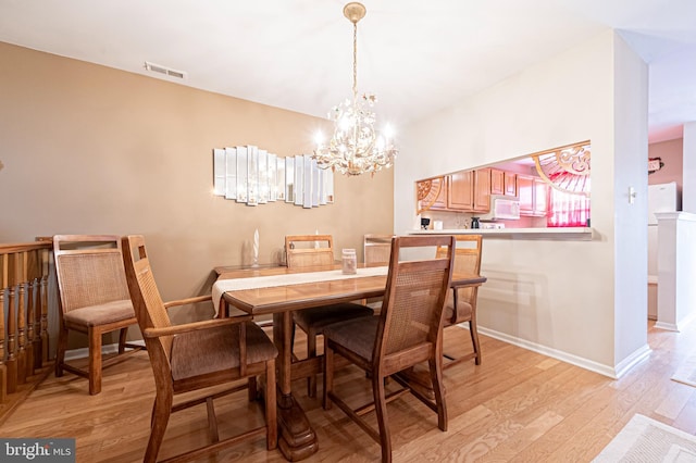 dining space featuring light hardwood / wood-style floors and a chandelier