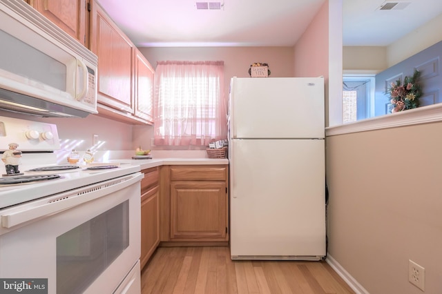 kitchen featuring light brown cabinets, white appliances, and light hardwood / wood-style flooring