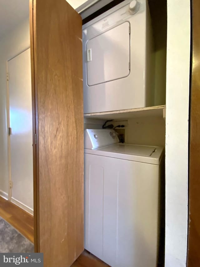 washroom with laundry area, stacked washer / drying machine, and wood finished floors