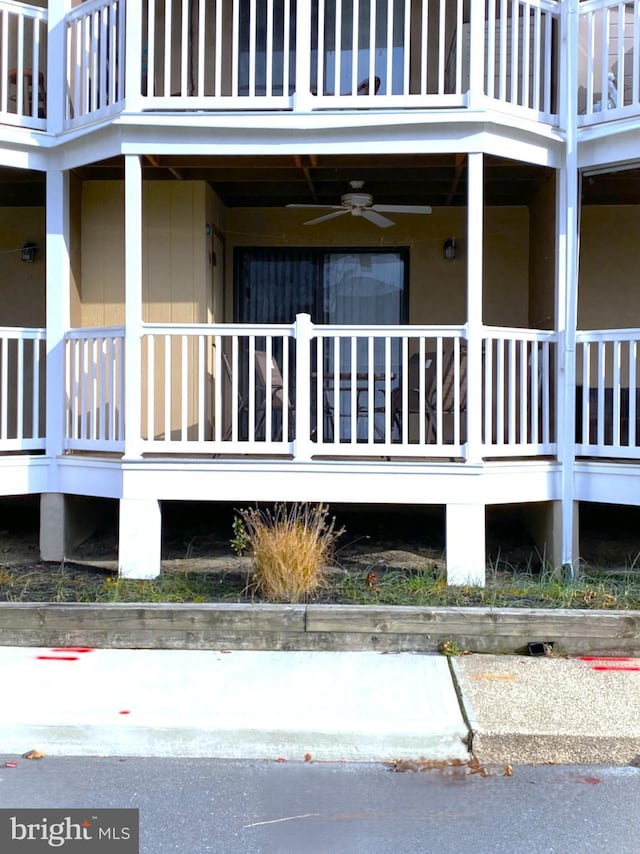 view of exterior entry with a balcony, a porch, and ceiling fan