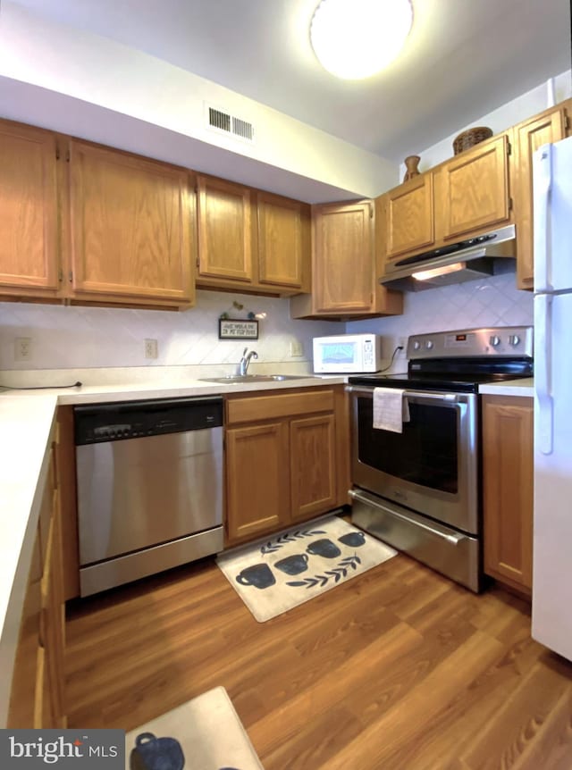 kitchen featuring visible vents, under cabinet range hood, light countertops, wood finished floors, and stainless steel appliances