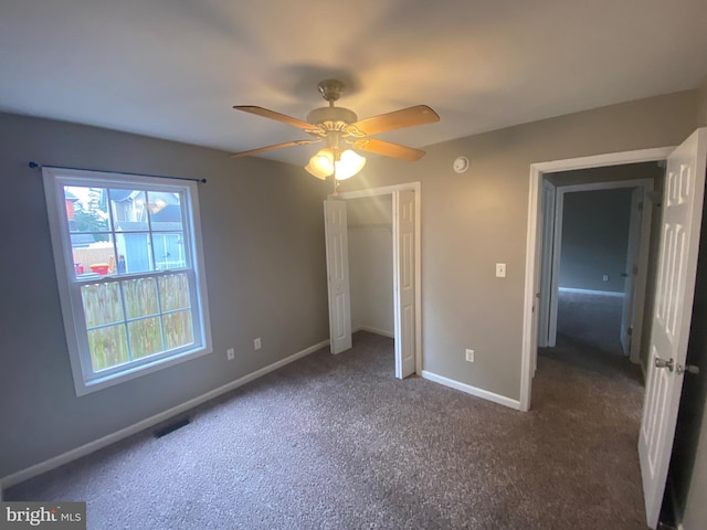 unfurnished bedroom with dark colored carpet and ceiling fan