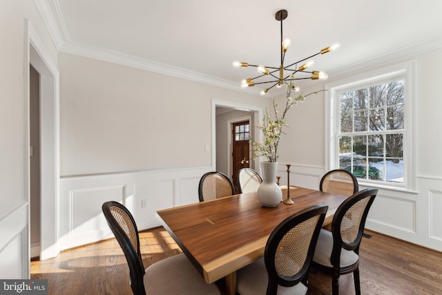 dining room with ornamental molding, dark wood-type flooring, an inviting chandelier, and a healthy amount of sunlight