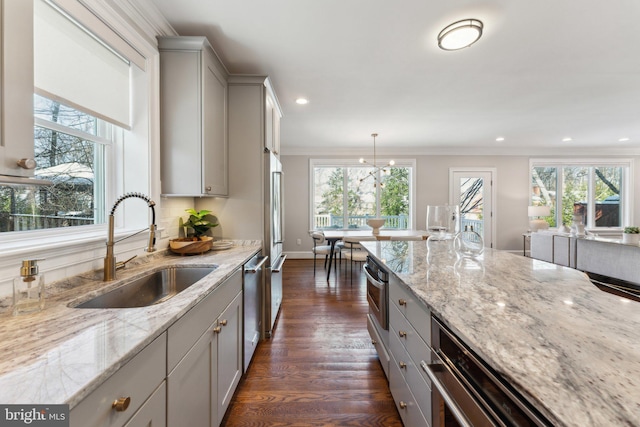 kitchen with pendant lighting, gray cabinets, light stone counters, and sink