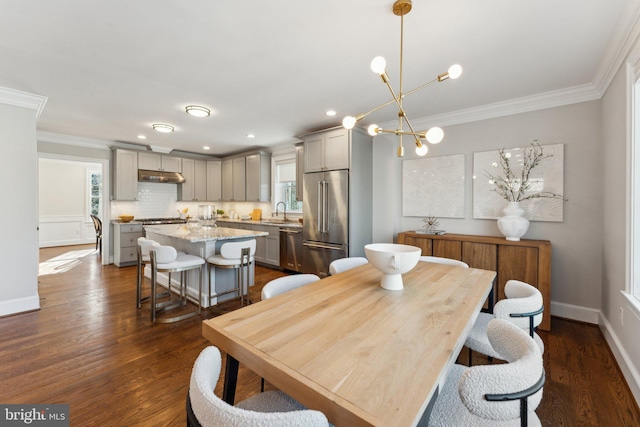 dining area with an inviting chandelier, crown molding, sink, and dark wood-type flooring