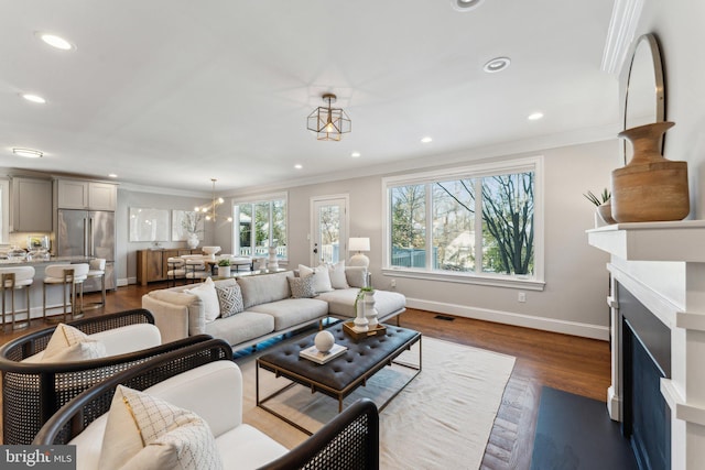 living room featuring crown molding, dark hardwood / wood-style flooring, and a notable chandelier