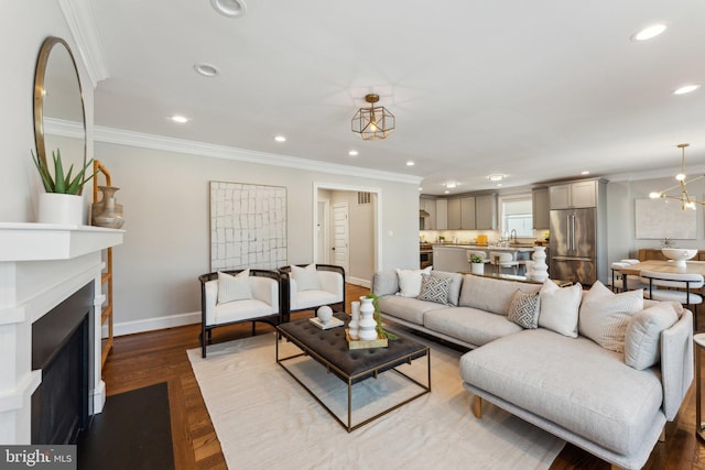 living room with hardwood / wood-style flooring, a notable chandelier, ornamental molding, and sink