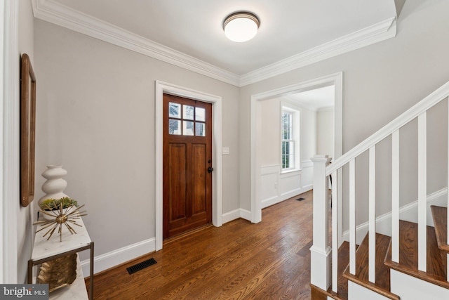 foyer entrance with dark hardwood / wood-style floors, a healthy amount of sunlight, and ornamental molding