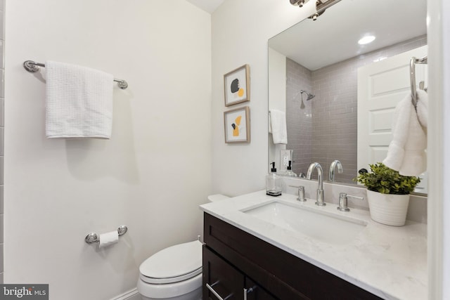 bathroom with a tile shower, vanity, and toilet