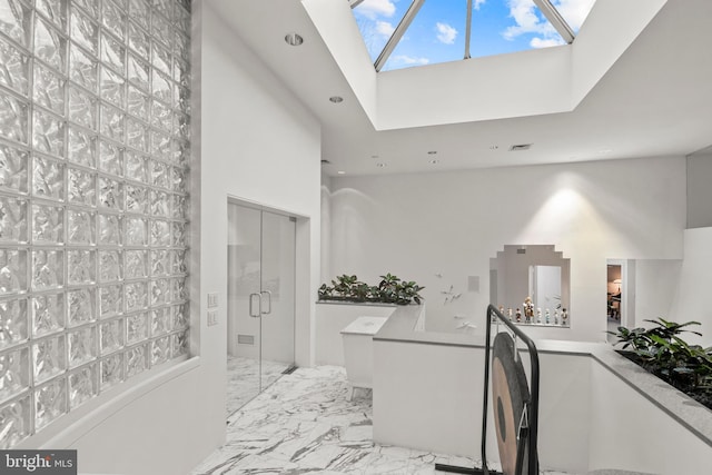 bathroom with a skylight and a towering ceiling