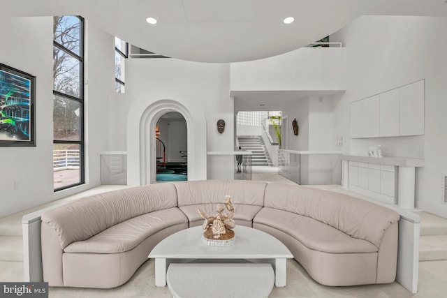 living room with a towering ceiling and light colored carpet