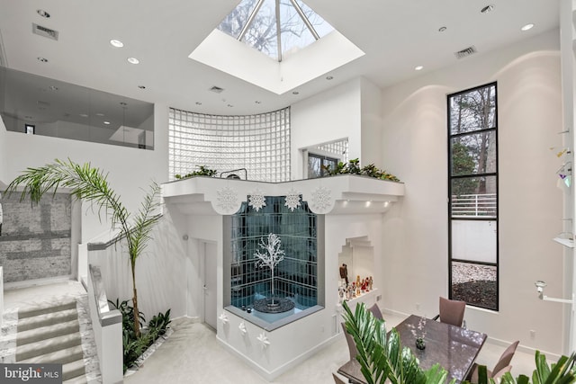 living room with a towering ceiling and a skylight