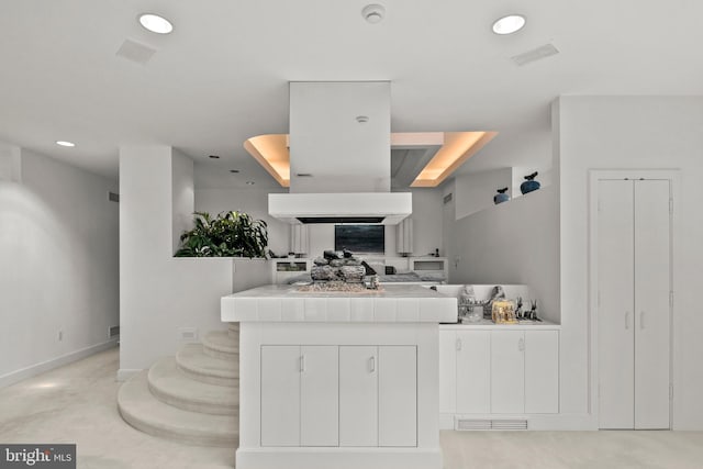 kitchen featuring tile counters and white cabinetry