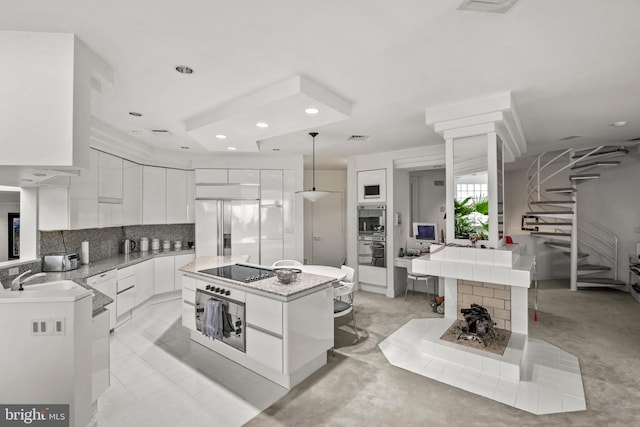 kitchen featuring white cabinetry, hanging light fixtures, backsplash, a kitchen island, and appliances with stainless steel finishes