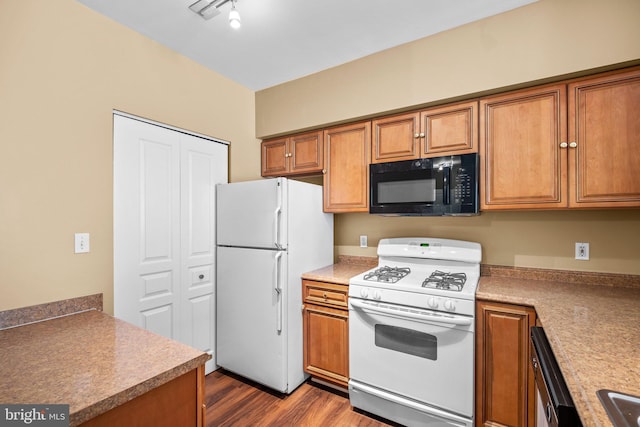 kitchen featuring white appliances, dark hardwood / wood-style floors, rail lighting, and sink