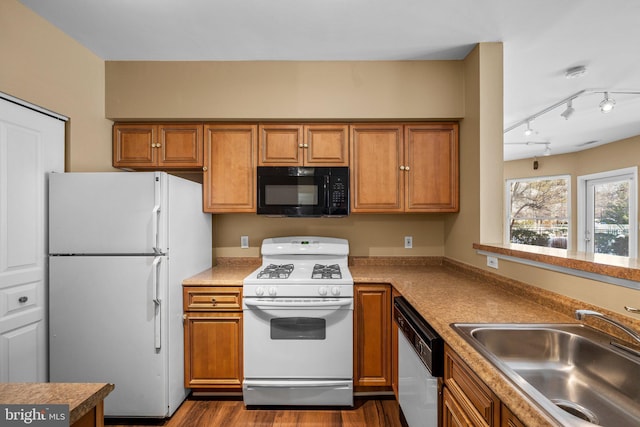 kitchen featuring white appliances, rail lighting, dark wood-type flooring, and sink