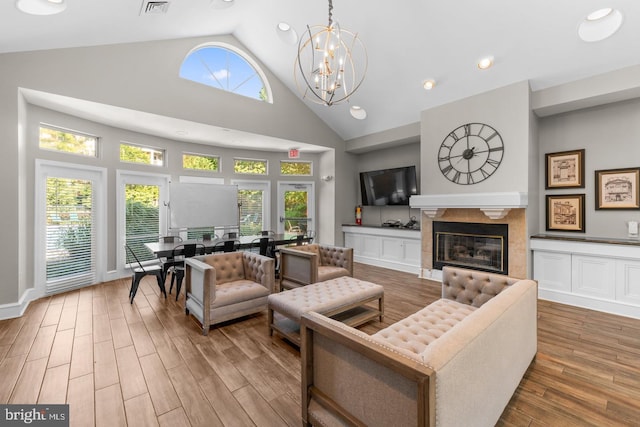 living room featuring a wealth of natural light, a high ceiling, a tile fireplace, and a chandelier