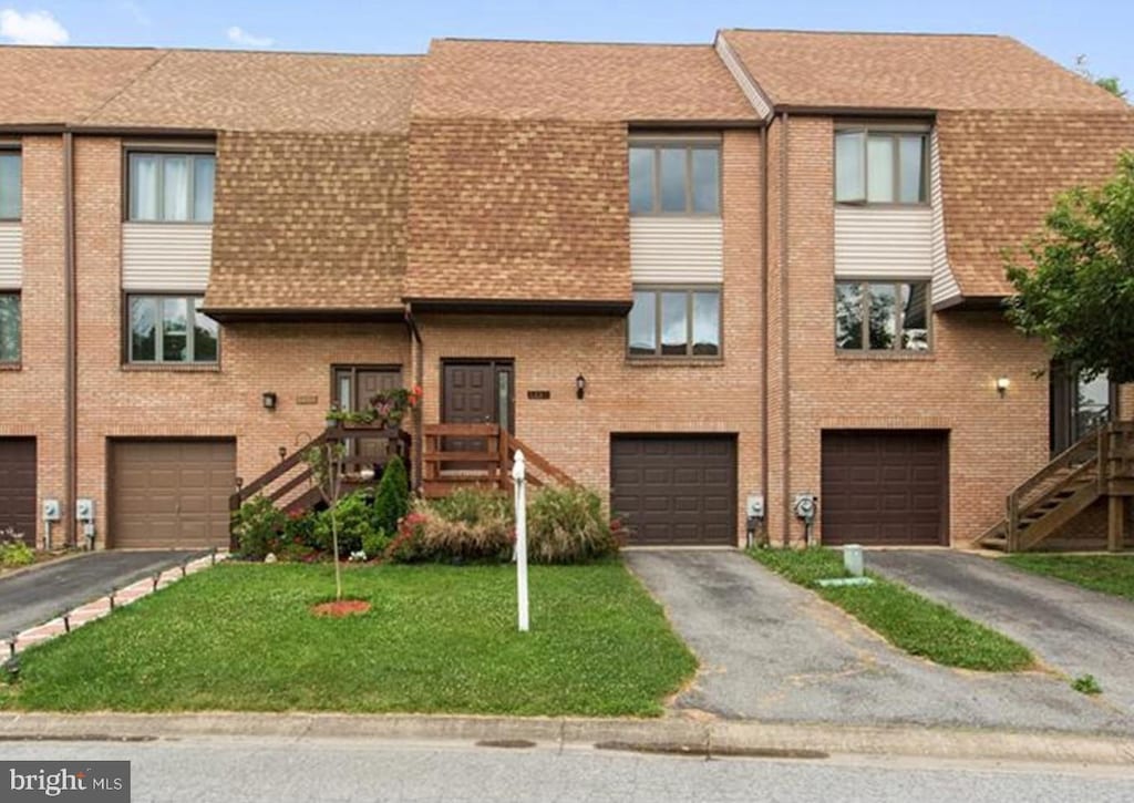 townhome / multi-family property featuring a garage and a front lawn