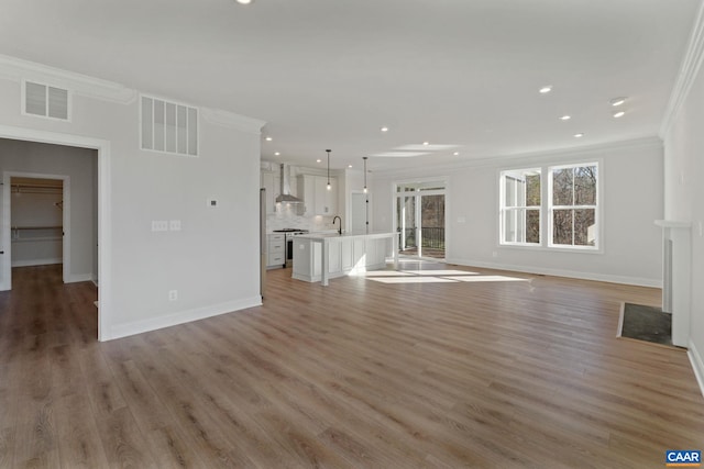 unfurnished living room featuring sink, light hardwood / wood-style flooring, and ornamental molding