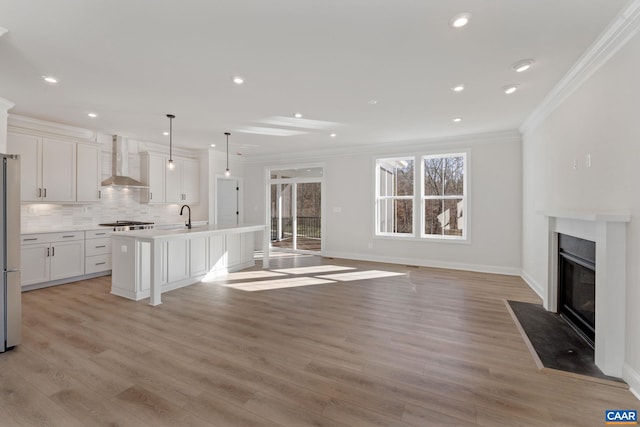 unfurnished living room featuring crown molding, sink, and light wood-type flooring