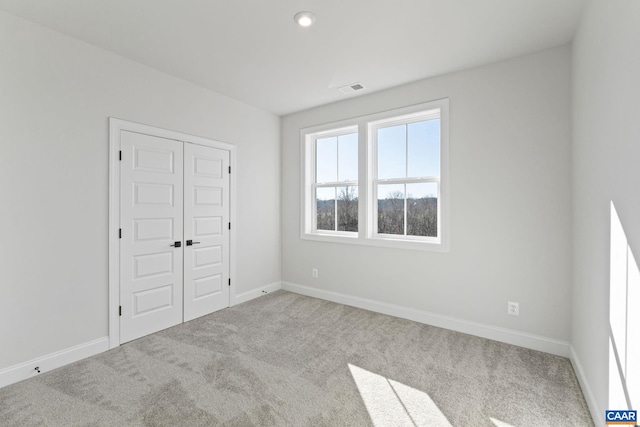 unfurnished bedroom featuring light carpet and a closet