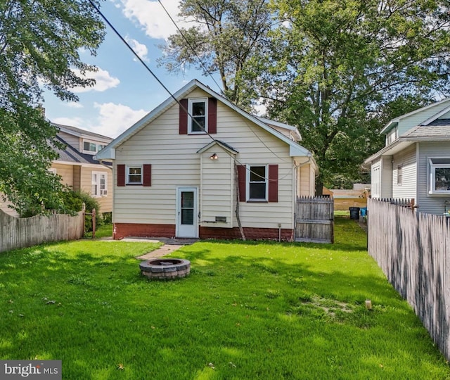 back of property with a fire pit and a lawn