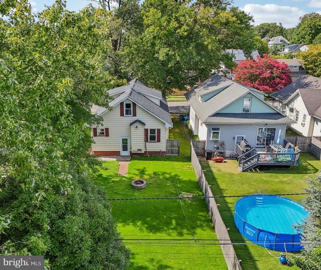 rear view of house featuring a swimming pool side deck, an outdoor fire pit, and a lawn