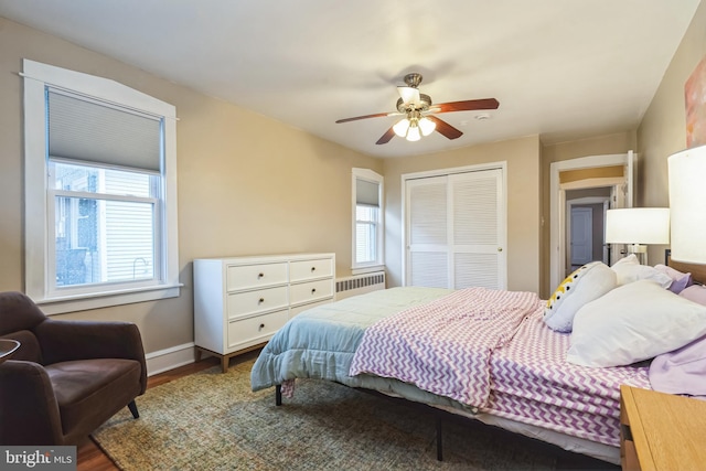 bedroom featuring a closet, ceiling fan, radiator heating unit, and wood-type flooring