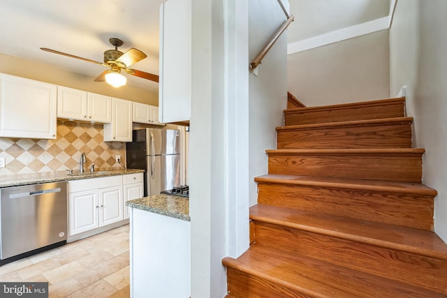 stairs with ceiling fan and sink