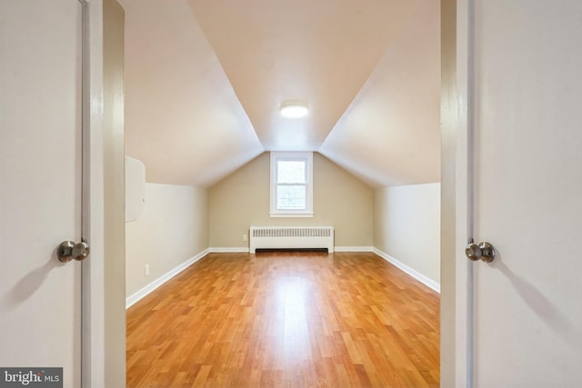 bonus room with lofted ceiling, light hardwood / wood-style floors, and radiator heating unit