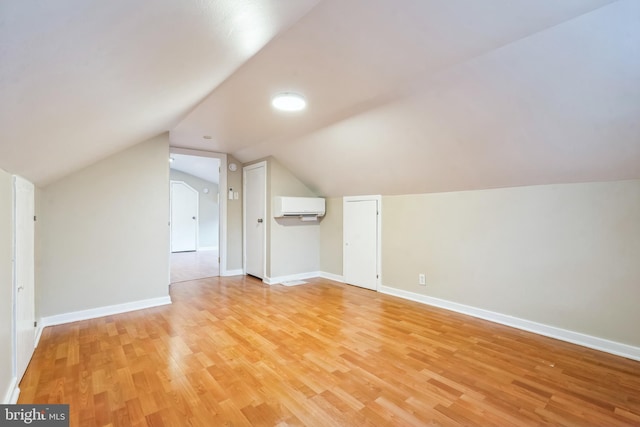 bonus room with a wall mounted AC, light hardwood / wood-style floors, and lofted ceiling