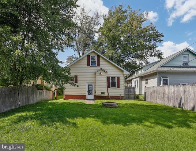 rear view of property with a lawn and an outdoor fire pit