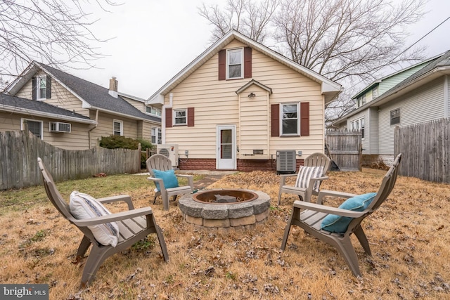 rear view of house with cooling unit and a fire pit