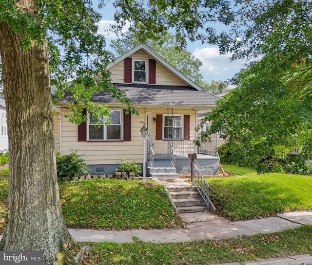 bungalow-style home featuring covered porch and a front lawn